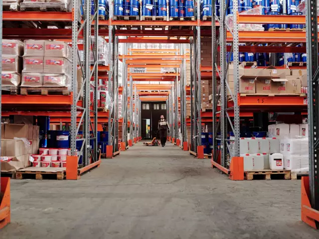 Aisle of a warehouse with stock on tall orange racking